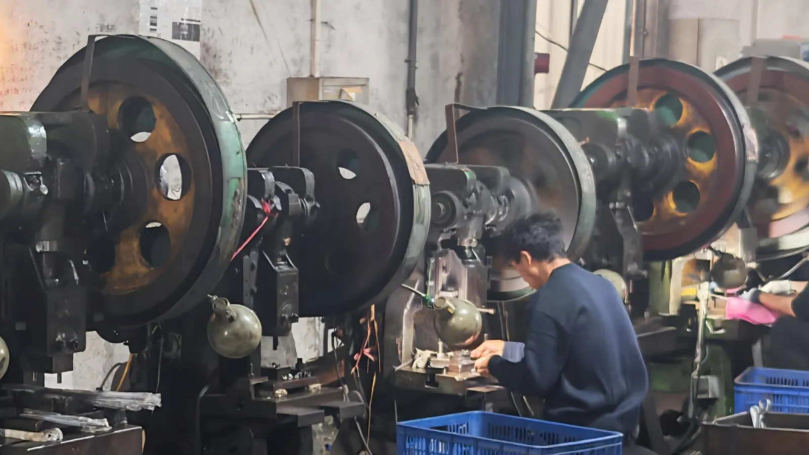 A worker at a flywheel press on the press-shop floor of a cookware factory