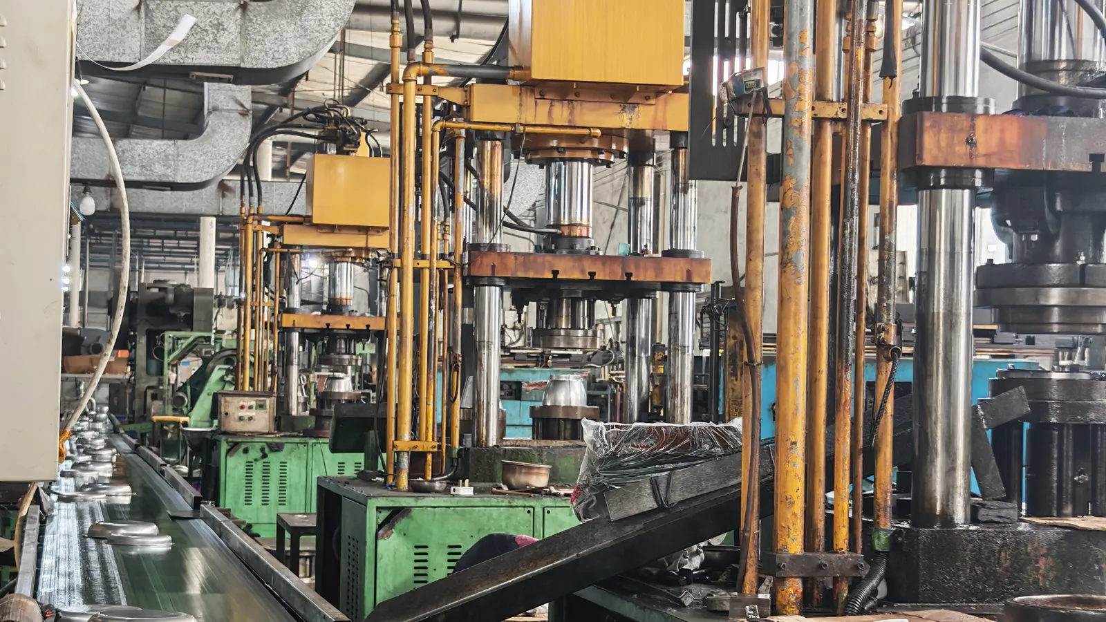 Rows of hydraulic press frames and forming equipment standing in the press hall of a stainless steel cookware factory