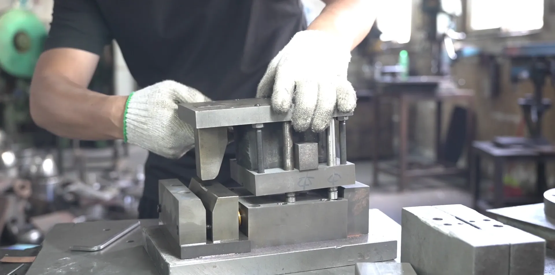 Factory operator fitting a die and locating blocks on a press, the tooling setup a first-run MOQ pays for