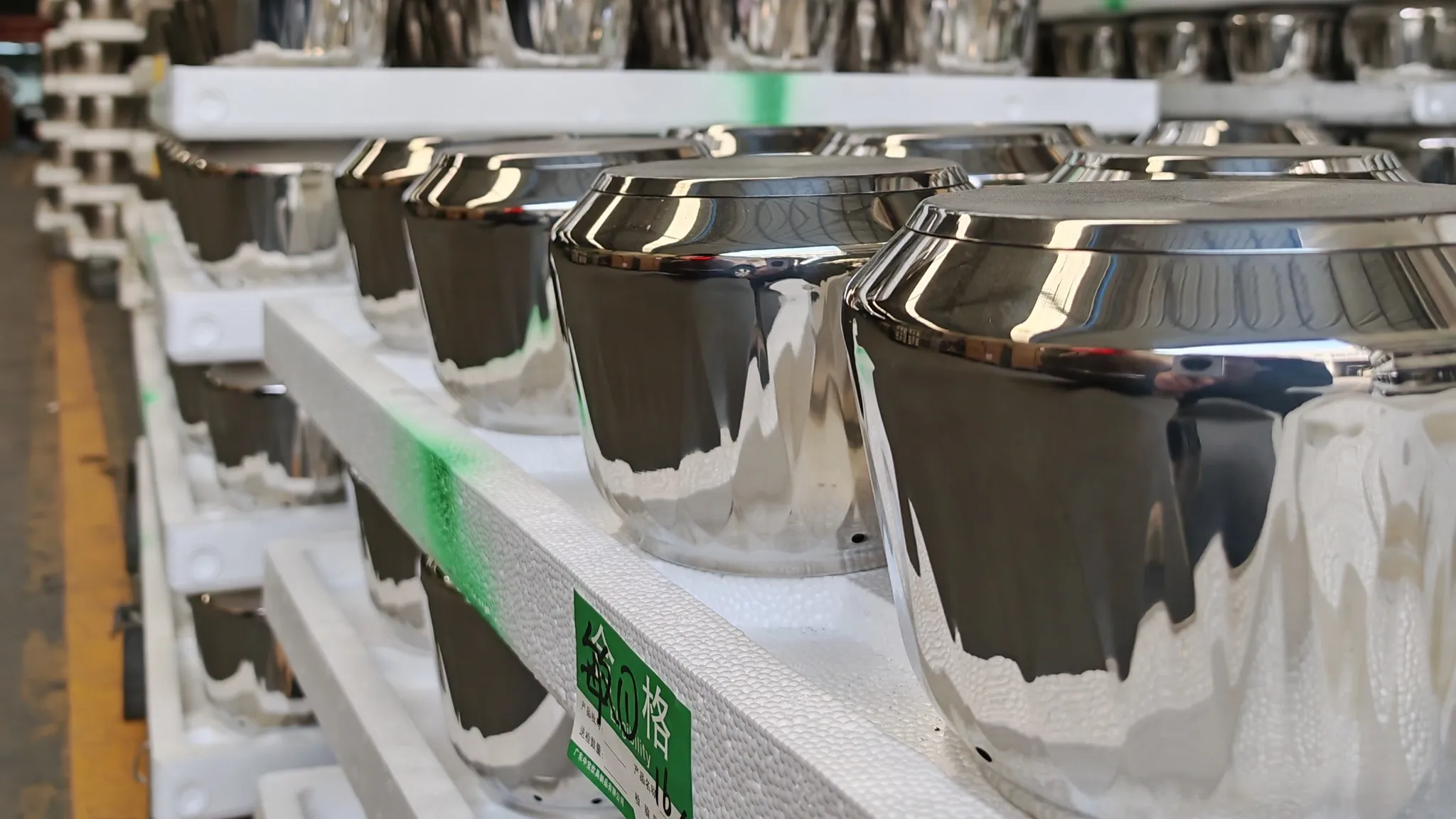 Finished stainless steel bodies on racks with a green inspection tag attached