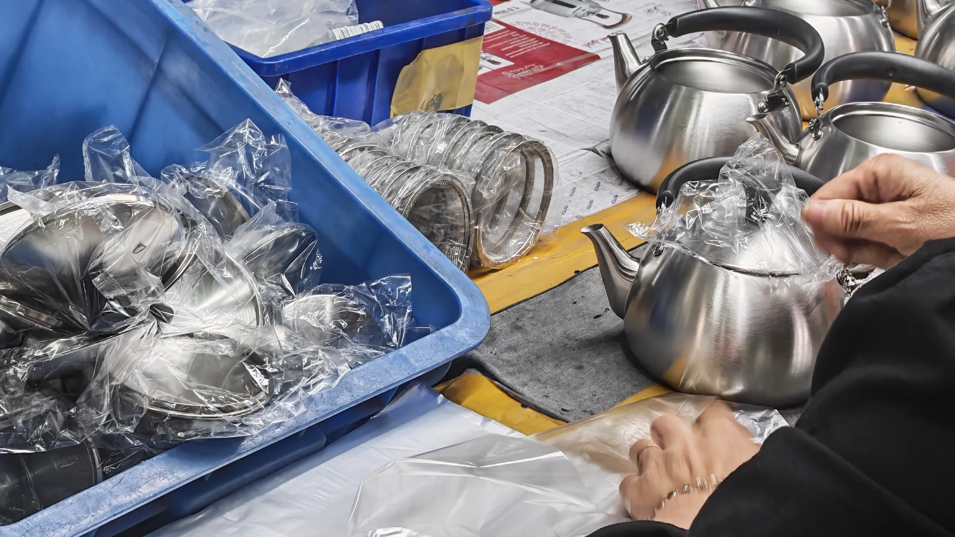 Worker bagging finished stainless steel kettles on the packing line — the final quality checkpoint before export cartons are sealed