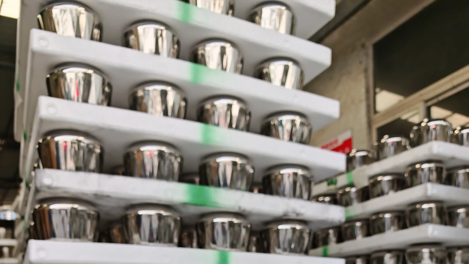 Mirror-polished stainless steel cookware bodies staged on racking between process steps, awaiting packing and inspection