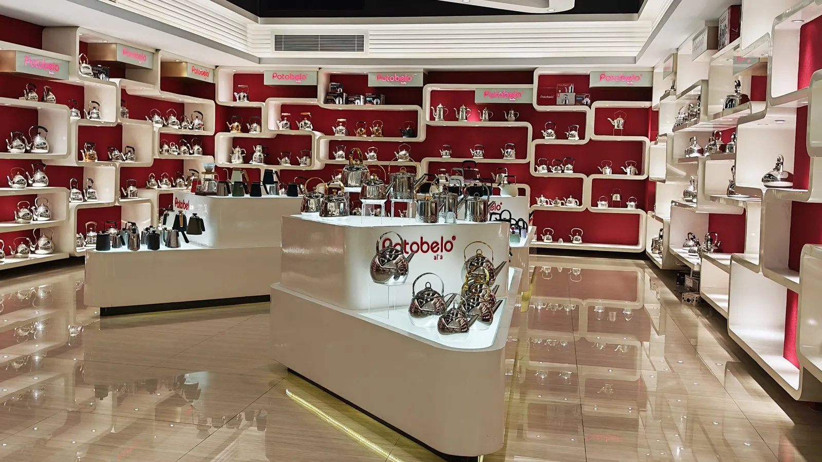 Rows of stainless steel kettles and teapots on a mirrored display wall in a cookware showroom